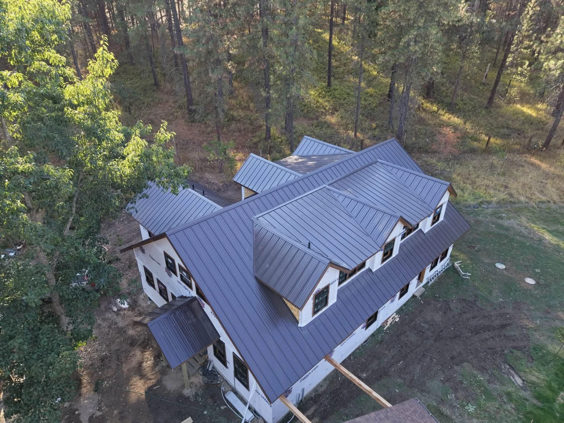 Aerial view of a Ridge Roofing standing seam metal roof project surrounded by trees