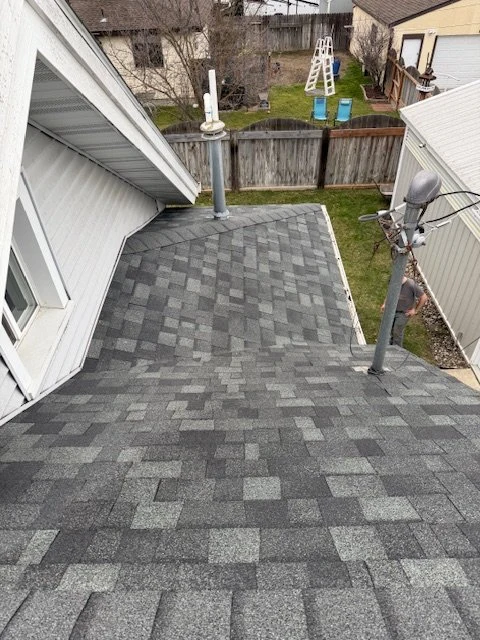 Finished shingle roof detail beside a house